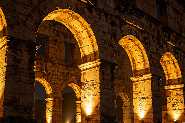 A historic stone bridge with its arches highlighted by powerful flood lights